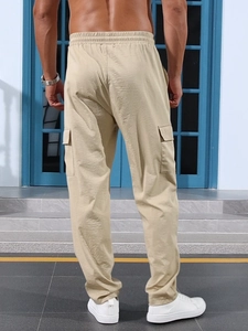 Detail view of khaki straight-leg cargo pants with elastic waist and back pockets