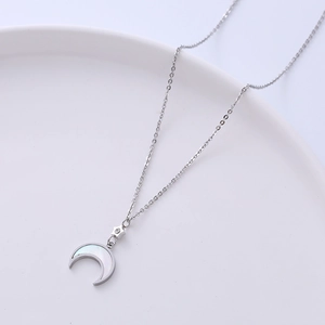 Silver star and crescent moon necklace with mother of pearl inlay on white plate