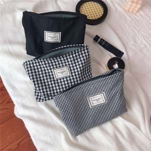 Three-piece black and checkered canvas cosmetic bags with zipper closure and soft lining