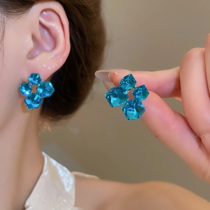 Close-up of geometric blue crystal earrings with 18k gold plating on silver studs