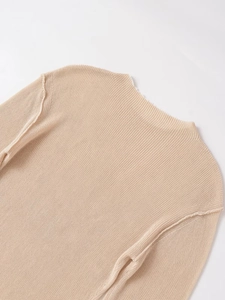 Close-up of the beige knit sweater neckline and drop shoulder seam detail
