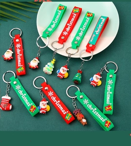Flat lay of colorful PVC Christmas keychains featuring Santa and trees on a green tray