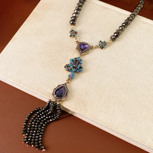 Détail d'un collier vintage avec perles de verre violettes et pompon noir sur un livre