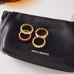 Macro detail of four gold-plated stacking rings with colorful cubic zirconia on black leather