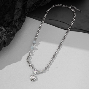Minimalist silver拼接 necklace with heart pendant and blue beads on stone background