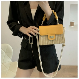Detail of yellow leather flap and straw woven crossbody bag with a twist lock closure