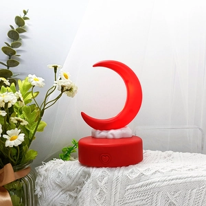 Close-up of red crescent moon night light with heart button on circular base