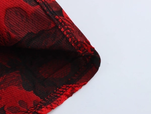 Macro shot of red and black jacquard fabric texture with intricate woven floral patterns