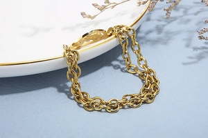 Detail of a gold-plated double-layer chain bracelet featuring a hollow Tree of Life pendant