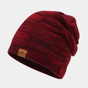 Detail showing the thick red and black knit texture and leather mountain patch on the winter hat