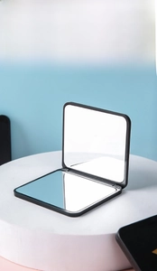 Detail of a portable black double-sided folding mirror on a minimalist display stand