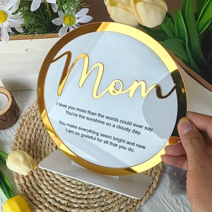 Detailed view of an acrylic Mother's Day plaque with gold border held by hand