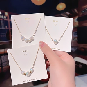 Detailed close-up of golden titanium necklaces with iridescent mermaid pearls on cards