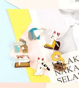 Detail view of 6 enamel cat and polar bear pins displayed on magazine background