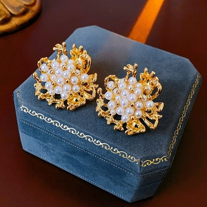 Dettaglio di orecchini vintage a corallo dorato con perle bianche in una scatola blu
