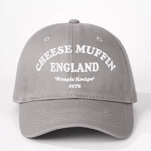 Close-up of white CHEESE MUFFIN embroidery on gray cotton twill baseball cap