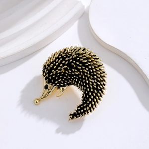 Exquisite gold and black hedgehog brooch with textured spines on a minimalist white stand