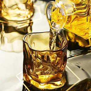 Amber origami style whiskey glass being filled with golden liquid in elegant motion
