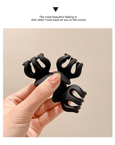 Close-up of a matte black claw clip for ponytails held by hand to show size and texture