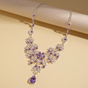 Detailed shot of a purple teardrop gemstone necklace with intricate floral silver chain