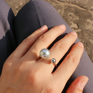 Detail of silver U-shaped open ring featuring a large grey pearl on the hand