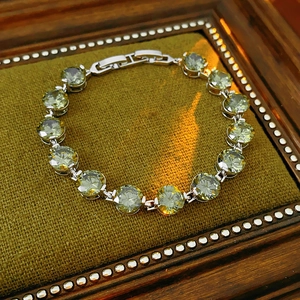 Close-up of silver chain bracelet featuring round green zircon stones on moss velvet pad