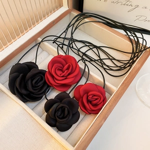Detailed view of handmade fabric rose necklaces in red and black inside a wooden box