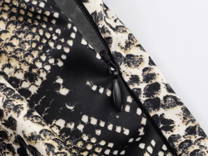 Detailed macro view of the invisible black zipper and snake print fabric of the midi skirt