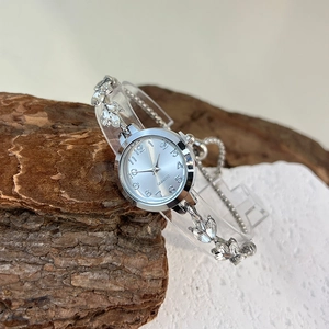 Macro shot of silver quartz watch with leaf-shaped rhinestone bracelet on natural stone