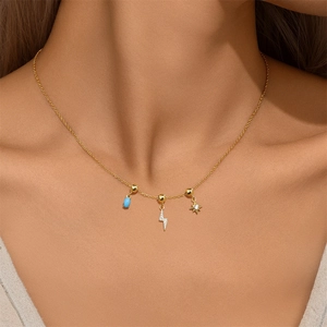 Close-up of gold S925 silver necklace with blue bead, lightning and star charms on model