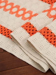 Close-up of vintage orange woven cotton table runner with fringe and geometric patterns