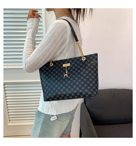 Dettaglio borsa shopper nera con motivo geometrico, catena dorata e ciondolo