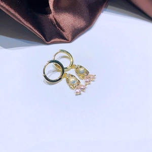 Details von goldenen Creolen mit birnenförmigem rosa Kristall und schillerndem Opal