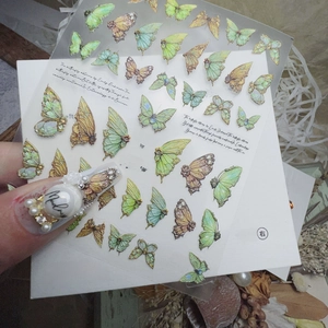 Detail view of 3D embossed green swallowtail butterfly nail stickers on vintage background