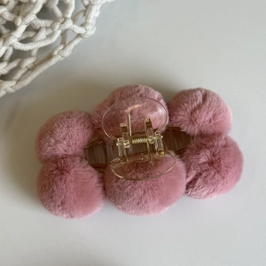 Top view of pink plush ball hair claw clip with transparent plastic base on white backdrop