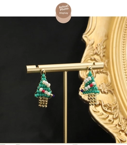 Detail of handmade Christmas tree beaded earrings with natural pearls and gold finish