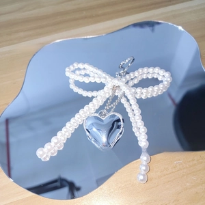 Detailed shot of a pearl beaded bow charm with a polished silver heart pendant