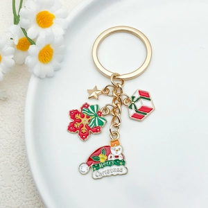 Golden Christmas keychain with festive charms like snowman and snowflake on white plate