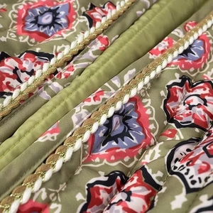 Macro view of olive green quilted fabric with floral print and woven decorative rope