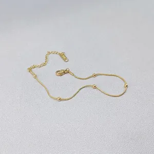 Close-up of 18K gold snake chain necklace with beads and K18 hallmark on the tag