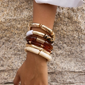 Stacked set of chunky bamboo resin bracelets in gold, leopard, and white finishes