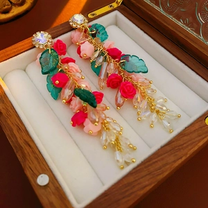 Gros plan de boucles d'oreilles vintage fleurs avec roses roses et pompons dorés