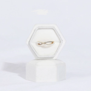Macro view of golden double-layer wave ring with pearls in white velvet hexagon box