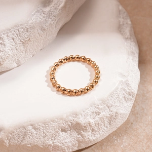 Dettaglio dell'anello con perline in oro rosa su base di pietra e finitura in metallo lucido