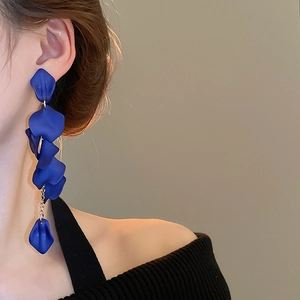 Close-up of matte blue rose petal tassel earrings worn by a model in a minimal style