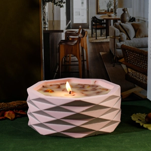 Pink geometric faceted concrete candle jar with dried flowers and glowing wick