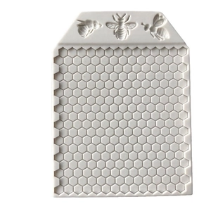 White silicone honeycomb cake mold with three detailed bee reliefs on white background