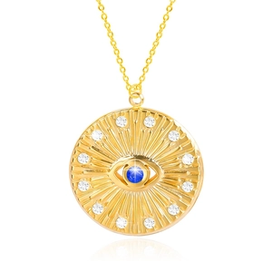 Detail of gold circular pendant with a blue eye gem and sparkling diamond accents