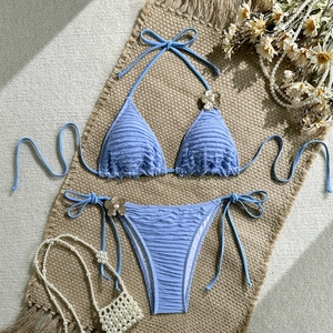 Detail of light blue bikini featuring textured fabric and floral pearl metal accents