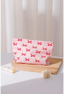 Detail of pink cotton makeup bag with red bow patterns and H&R BAG brand tag